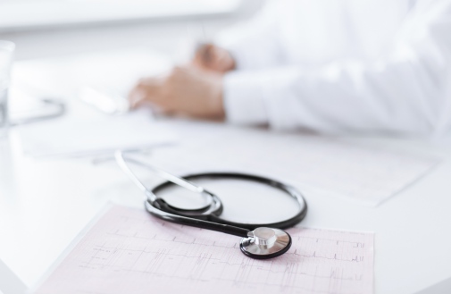 Foto manlig doktor Bild på en doktors händer och bredvid ligger ett stetoskop. Foto:Mostphotos.